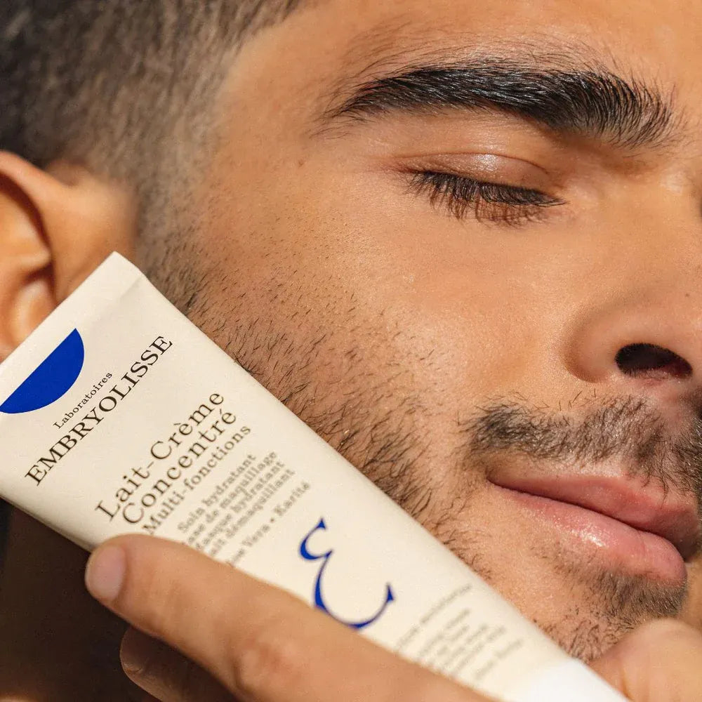 Man holding Embryolisse skincare product close to his face